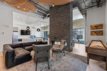 A modern living room with a black leather couch and a wooden coffee table.